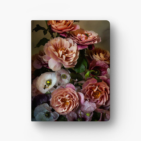 Photograph of the front cover a notebook. The cover is in full color and features pink roses and light colored poppies. One of the poppies has a honeybee sitting on it.